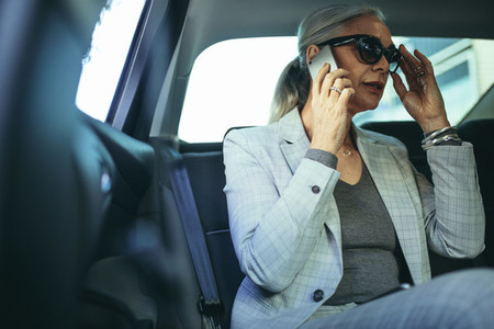 Senior female entrepreneur traveling to work in a luxury car