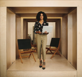 Portrait of a businesswoman standing in office holding laptop