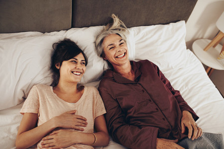 Top view of happy mother and daughter lying on bed