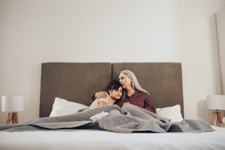 Woman sleeping in the arms of her mother on bed
