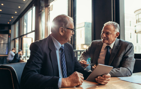Two senior businessmen having an informal meeting at cafe