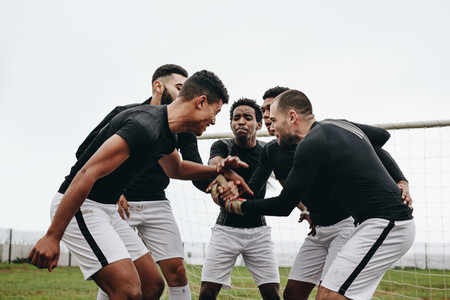 Soccer players joining hands standing in a huddle