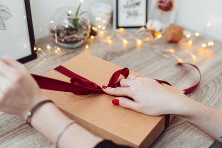 Woman wrapping present in paper with red ribbon