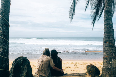 couple sitting under palm trees