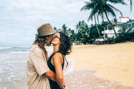 a guy and a girl are kissing on a beach