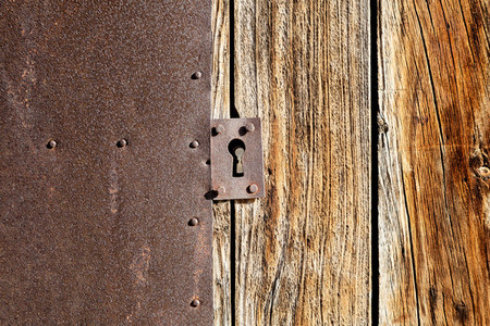 Close up antique lock on brown wooden door and rusty metallic texture