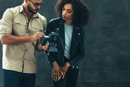 Photographer showing photos to a model on his camera