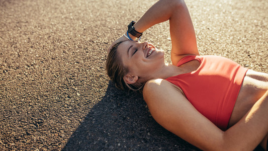 Woman athlete lying on ground relaxing during workout