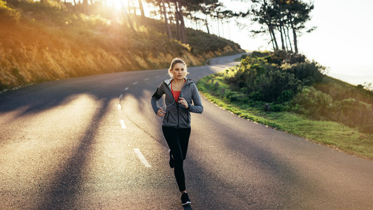 Woman athlete running on road in the morning