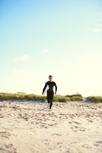 Athletic surfer running towards the surf