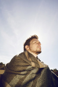 Side face of a young man with a warm scarf enjoying in calm the