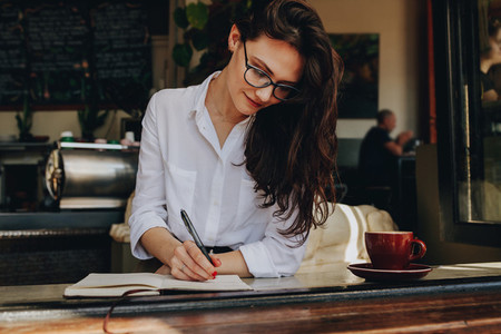 Woman writing in book at coffee shop