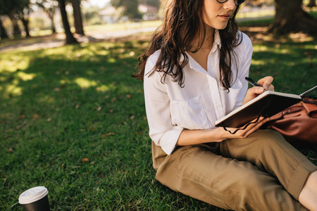 Woman relaxing at park and writing in book