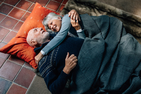 Senior couple sleeping together on floor