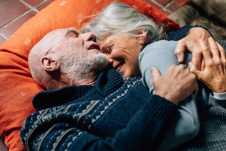 Senior couple lying on floor embracing each other