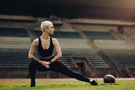 Woman athlete doing stretching exercises in a stadium
