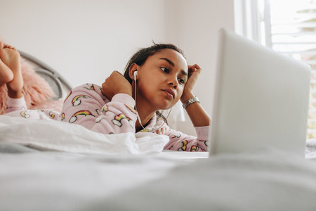 Girl looking at laptop lying on bed