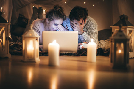 Couple enjoying a movie at night in bedroom