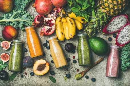 Colorful smoothies in bottles with fresh tropical fruit and superfoods