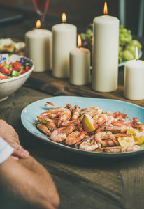 Salad  shrimps and candles on wooden table