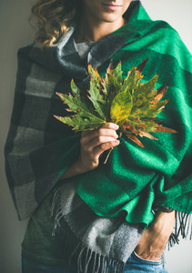 Woman in scarf or blanket and jeans with Autumn leaves