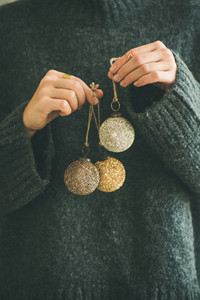 Woman in grey sweater holding golden and silver balls