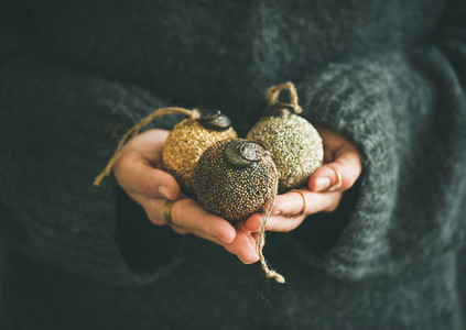 Woman in sweater holding golden and silver balls in hands