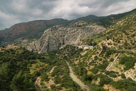 Train approaching a tunnel in a large valley in ardales  andalucia  surrounded by hills and a river
