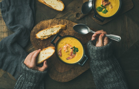 Woman in sweater eating corn soup with prawns  top view