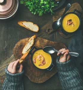 Woman in sweater eating corn creamy soup with shrimps
