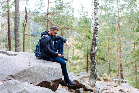 guy sits in the woods on a rock