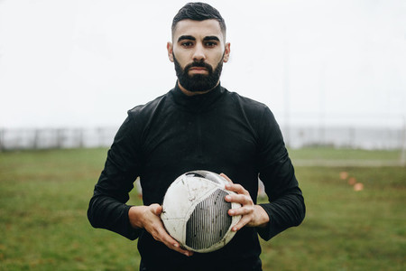 Portrait of a soccer player standing on field holding a ball