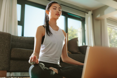 Woman practicing home yoga with laptop