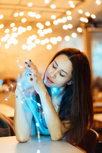 Woman holding glowing christmas garland in hands