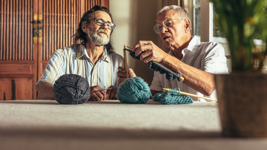 Senior man teaching his friends the art of knitting