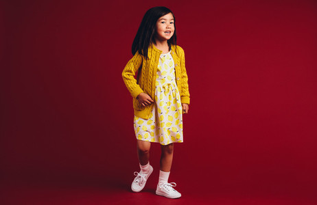 Little girl standing against a red background