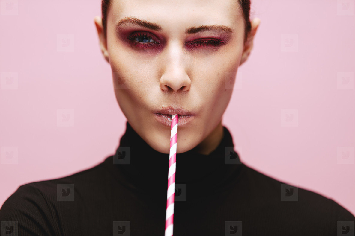Beautiful woman winking with a straw
