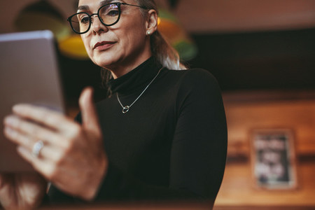 Senior woman at cafe using digital tablet