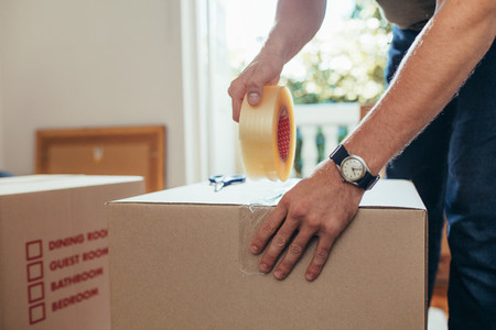 Close up of a man applying adhesive tape on a packing box