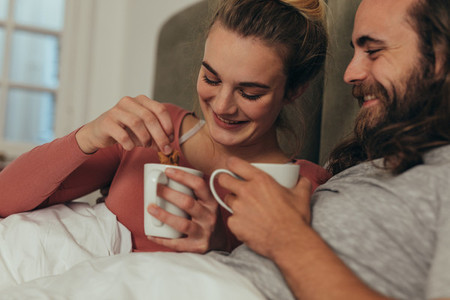 Happy couple drinking coffee in bed