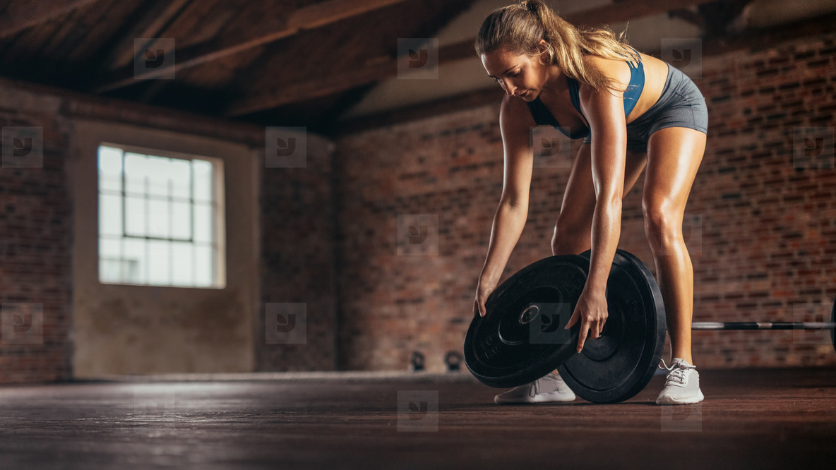 Athlete preparing weights for exercising at fitness club