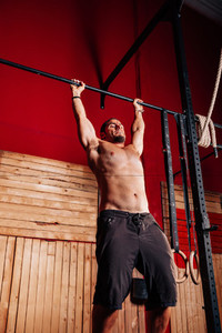 Athletic young man doing pull ups exercises without t shirt in a crossfit gym