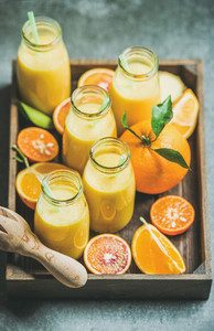 Healthy yellow smoothie in bottles in wooden tray