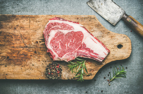 Raw beef steak rib eye on board with seasoning and knife