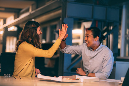 Cheerful business partners giving high five at office