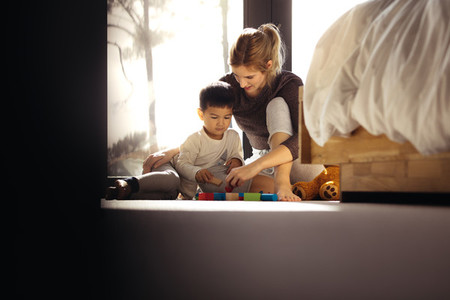 Mother and son playing with toys in bedroom