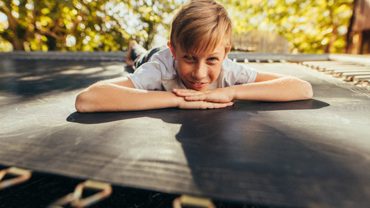 Small boy lying on trampoline outdoors