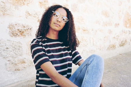 A portrait of serious young black woman wearing glasses  jeans a