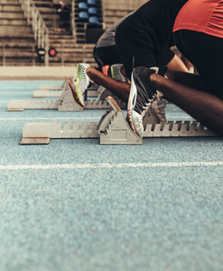Athletes resting their feet on starting blocks on running track