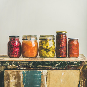 Autumn pickled vegetables in jars placed in line  square crop